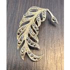 Винтажная брошь, выполненная в форме изящного пера.