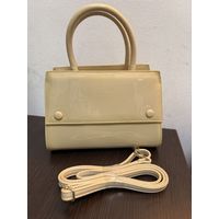 Элегантная женская сумка светло-бежевого цвета с лаковой поверхностью.